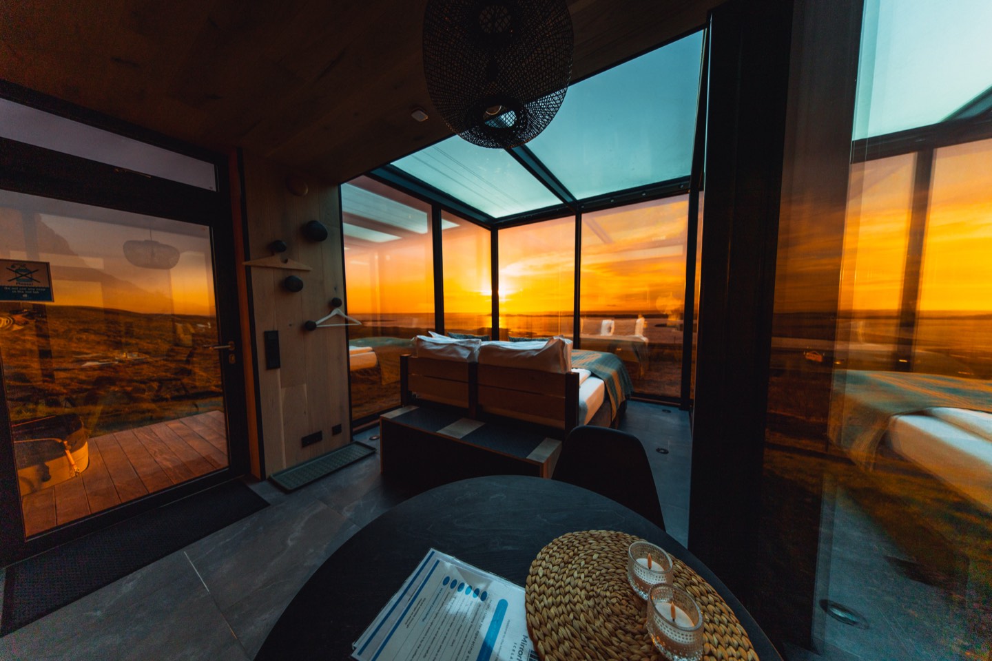 The room at sunset, glass walls on every side and the low sun over the water